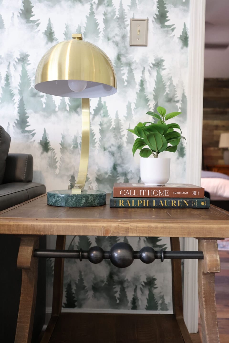 A cozy corner where the glow of a golden lamp meets the charm of forest-inspired wallpaper. This is the kind of spot that invites you to slow down with a good book and a warm drink.