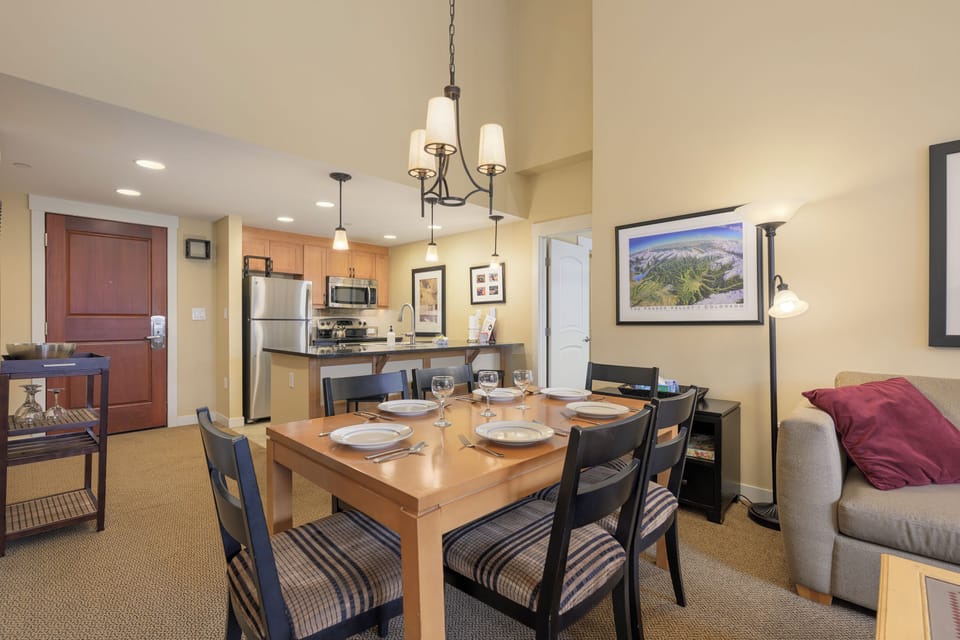 Your open-plan dining and kitchen space awaits memorable family meals with elegant chandelier lighting and mountain artwork setting the perfect ambiance.