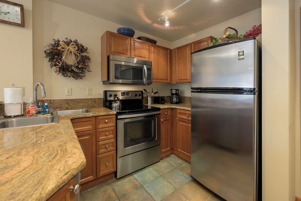 Your fully equipped kitchen awaits with modern stainless appliances, granite counters, and warm wood cabinets for all your culinary adventures.