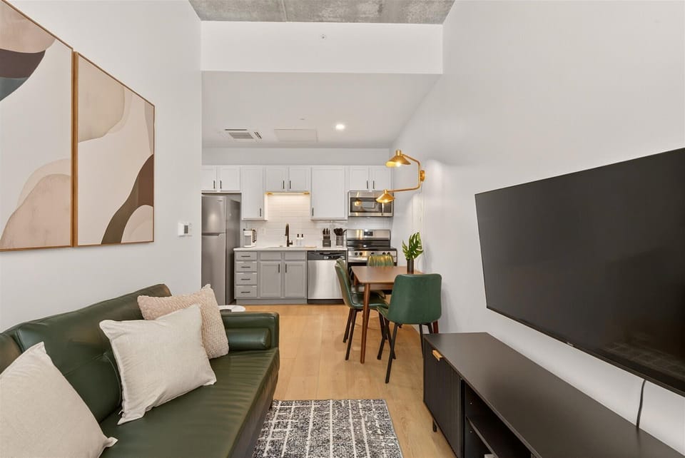 Bold green sofa + Smart TV in a bright, open-concept space designed for comfort, connection, and downtime.