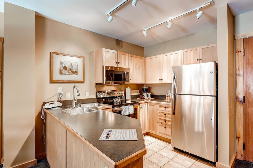 The fully equipped kitchen boasts modern appliances and warm wooden cabinetry, perfect for preparing delicious meals.