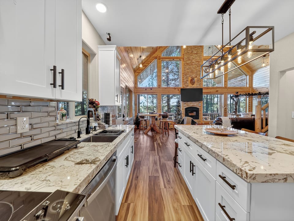 Your dream kitchen awaits with gleaming granite counters and warm hardwood floors flowing into an open great room where soaring windows frame stunning forest views.