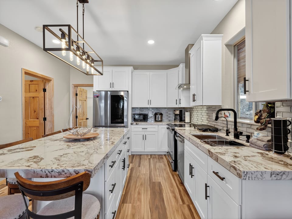 Spacious gourmet kitchen awaits with stunning marble countertops, modern stainless steel appliances, and elegant pendant lighting.