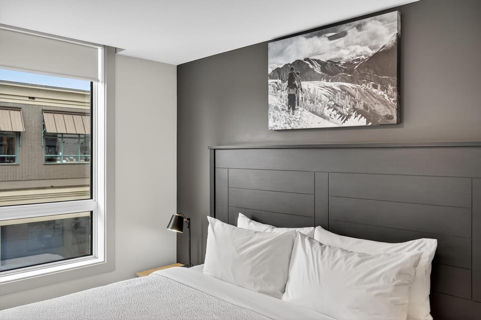 Framed by large windows that invite the outside world in, this serene bedroom combines elegance with practicality, offering a restful escape that captures the spirit of stylish mountain living in the heart of Revelstoke.