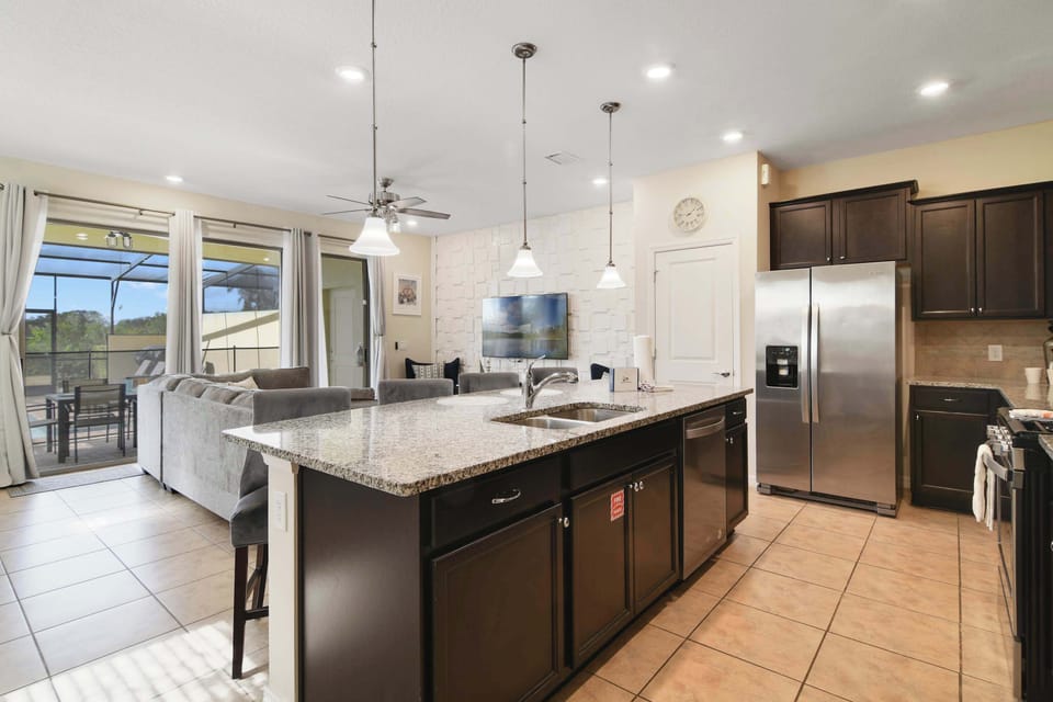 Modern kitchen with granite island and stainless steel appliances overlooking the living area.