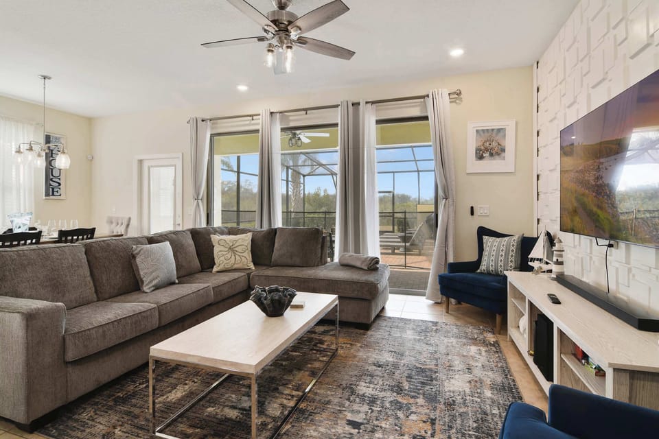 Modern living room with large sectional sofa and sliding glass doors leading to a screened patio