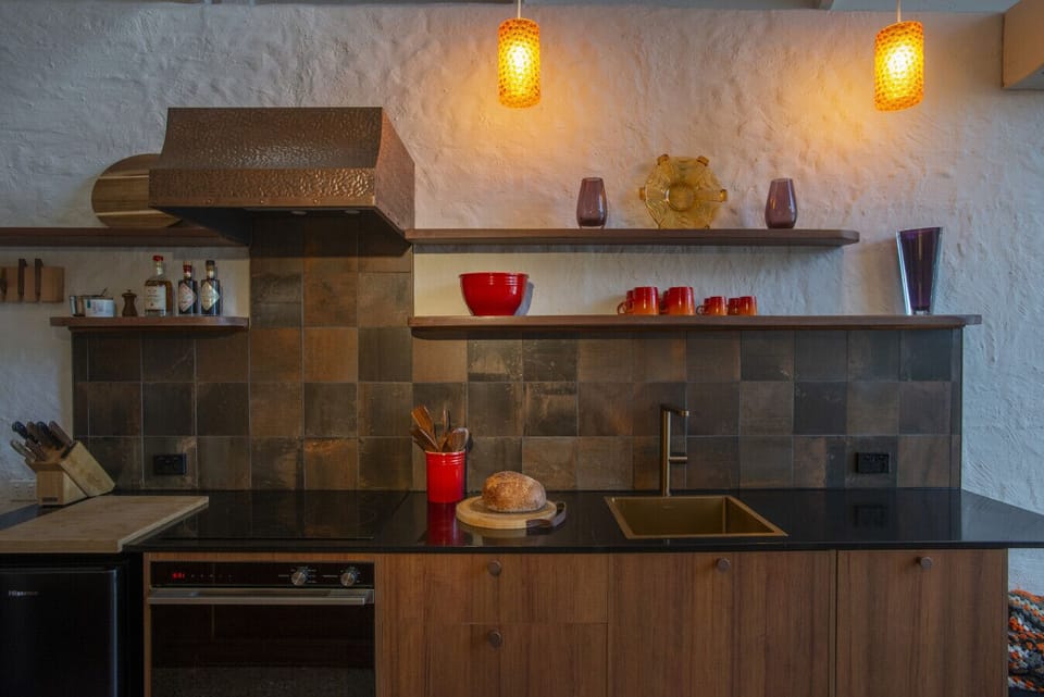 Cook up local produce with ease in the compact but functional kitchen, featuring open shelving and moody tile accents that add flair to your stay.
