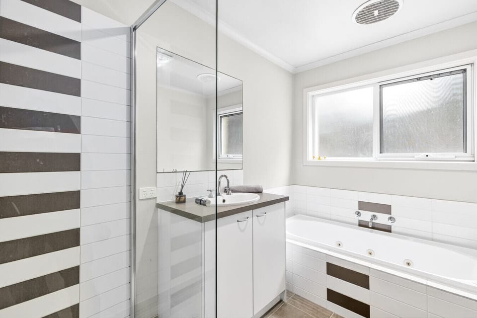 Clean and modern bathroom with bath, shower and bright finishes