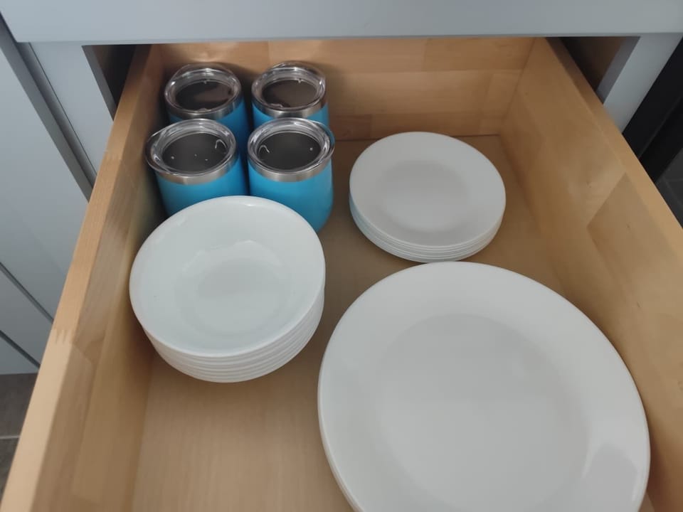 Kitchen cabinet with plates and travel wine tumblers for the beach. 