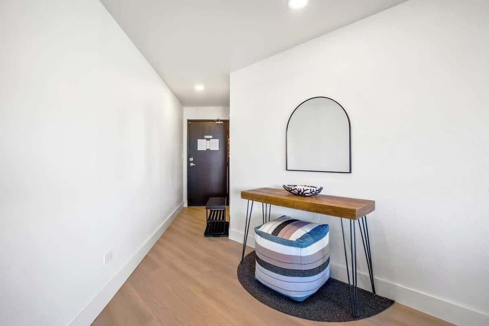 Welcome home to this bright, modern entry hallway, featuring a stylish console table with a decorative pouf, perfect for dropping your keys and preparing for your day.