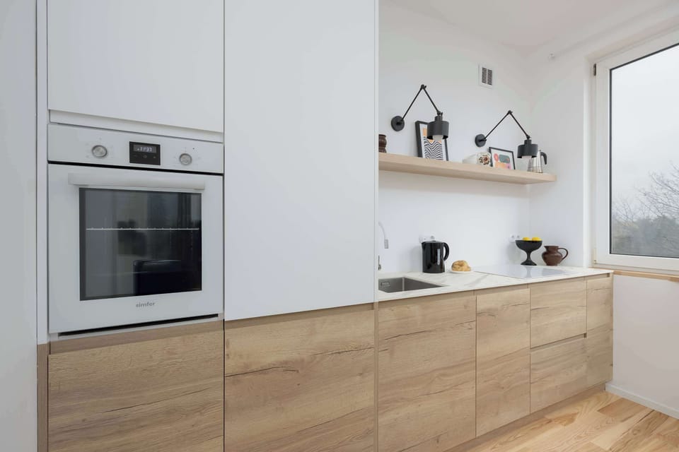 Modern, fully equipped kitchen with sleek white cabinetry, built-in appliances and warm wooden finishes.