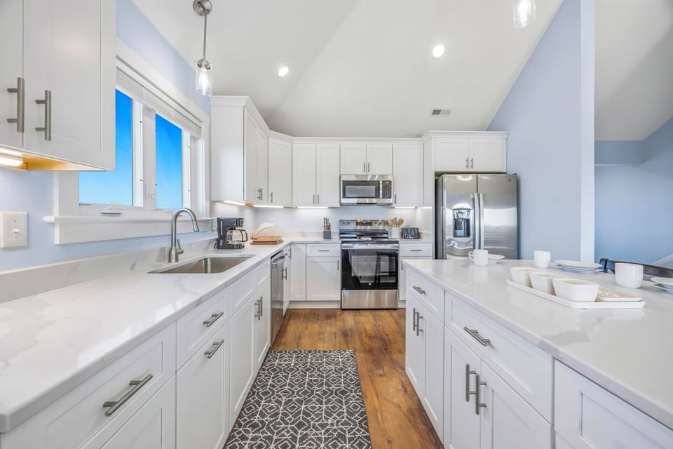 Your fully-equipped kitchen features gleaming white cabinets, quartz countertops, and modern stainless appliances, perfect for creating memorable meals together.