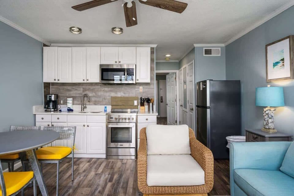 Compact kitchen with white cabinets, stainless steel appliances, and beachy decor.