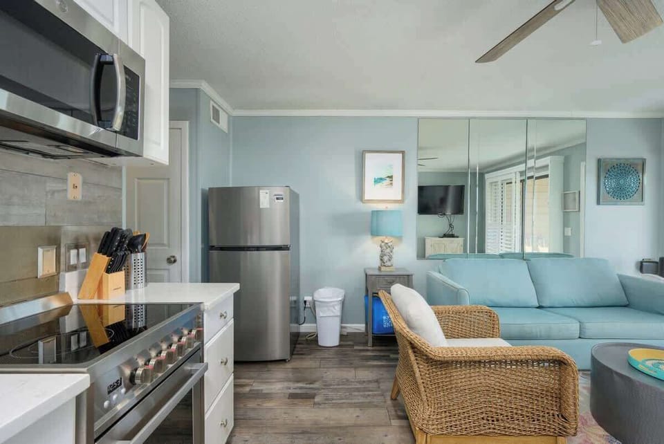 Features white cabinetry, including a microwave, and a full-sized refrigerator.
