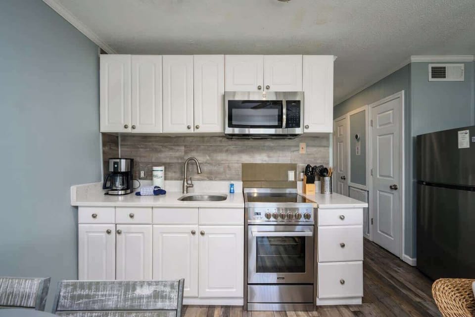 Fully equipped with white shaker cabinets and a wood-grain backsplash.
