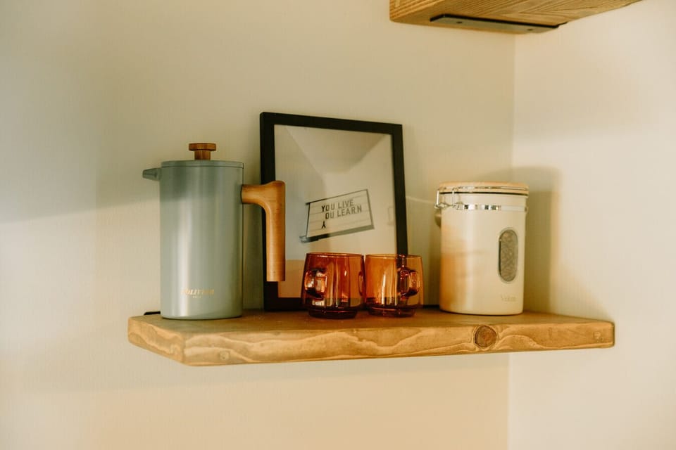 Our coffee bar includes whole beans, a grinder, a French press, amber coffee mugs, a Keurig, K-Cups, syrups, and sweeteners.