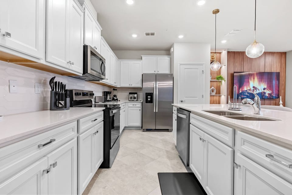 Discover a bright kitchen featuring sleek white cabinetry and modern stainless steel appliances. Spacious countertops inspire culinary creativity, and warm lighting creates a cozy atmosphere perfect for gatherings or casual meals.