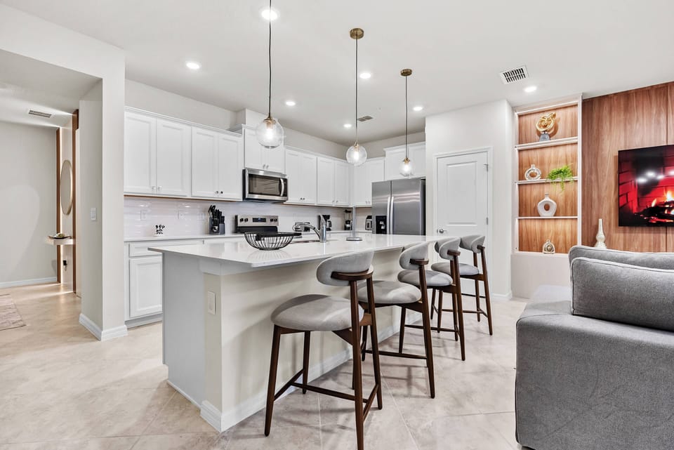 Welcome to a bright kitchen featuring sleek white cabinetry and a spacious island for casual dining. The warm wood accents and modern appliances create a cozy atmosphere for culinary adventures and gathering with loved ones.