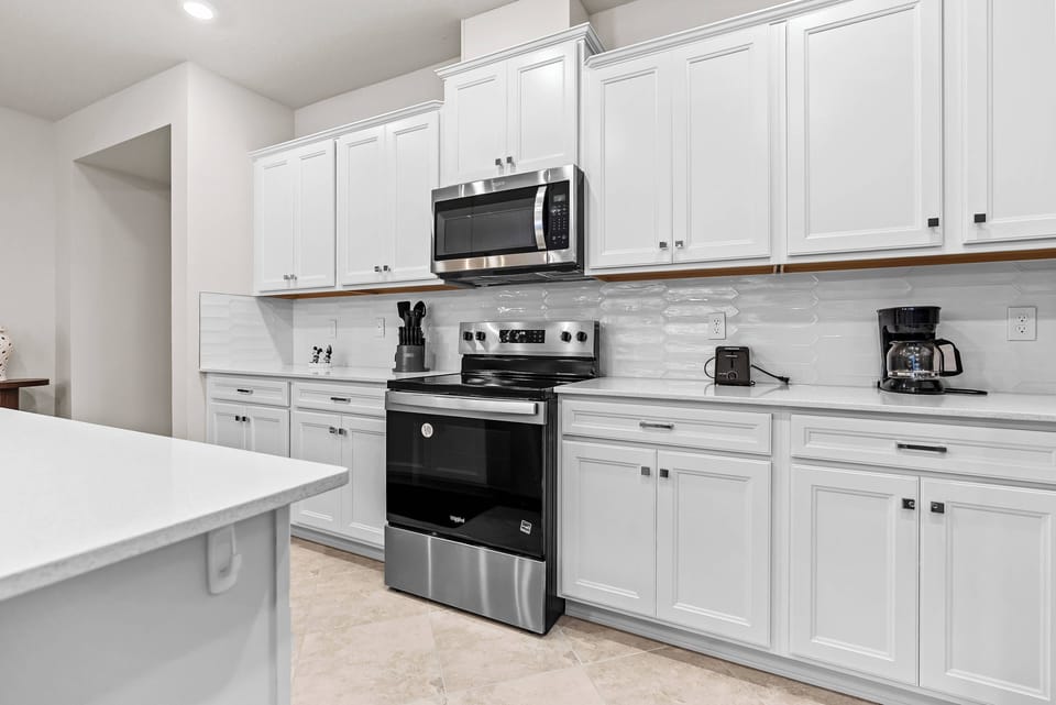 Experience a chic kitchen with sleek white cabinets that brighten the space. Modern stainless steel appliances inspire your cooking, while the spacious island offers ample room for meal prep or casual dining.