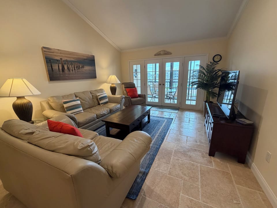 Relax in your comfortable living space with plush sectional seating, warm lighting, and French doors opening to your private balcony.