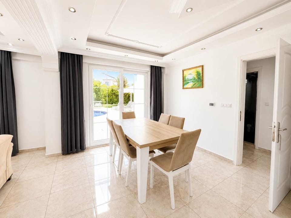 Bright dining area with elegant tiled floors, modern ceiling details, and direct access to the pool terrace.