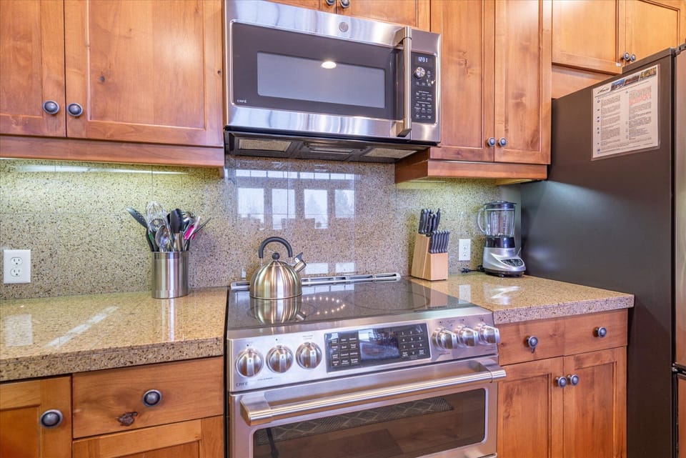 Your fully equipped kitchen awaits with warm wood cabinets, granite countertops, and stainless steel appliances: double oven, induction stove. large refrigerator, dishwasher, and microwave.