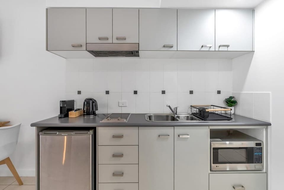 A compact, well-equipped kitchenette equipped with a cooktop, microwave, mini fridge, and all the essentials makes light self-catering simple and effortless.