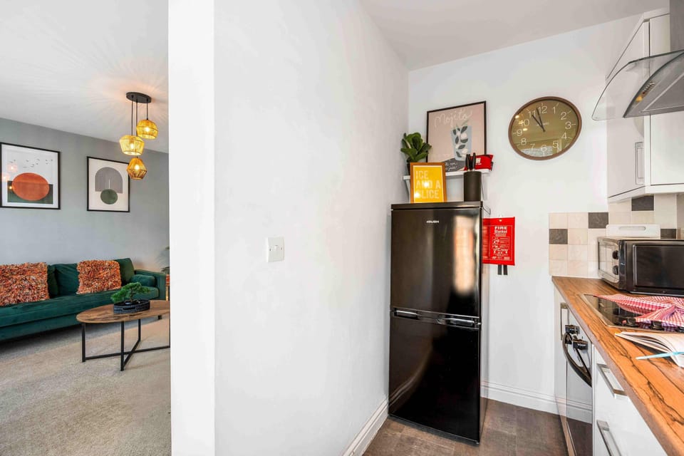 Open plan kitchen area with oven, kettle, and plenty of cookware, light pouring in from the living space.