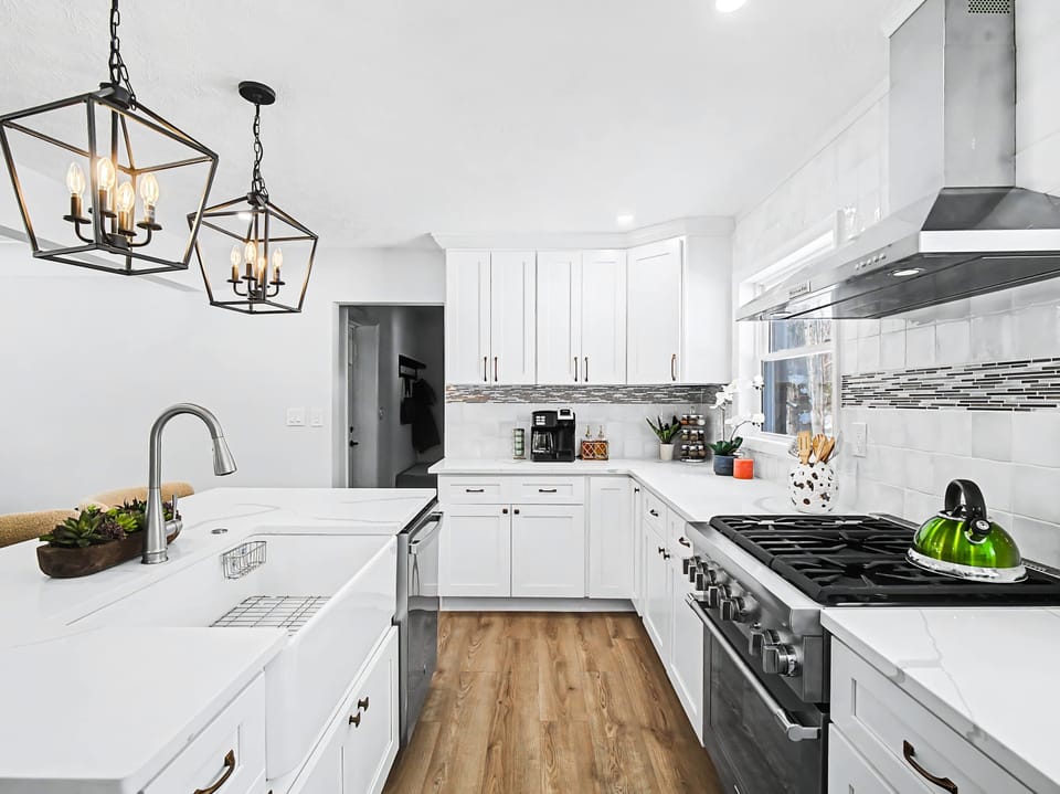 Sleek kitchen w/ long counters, stainless appliances & warm wood flooring