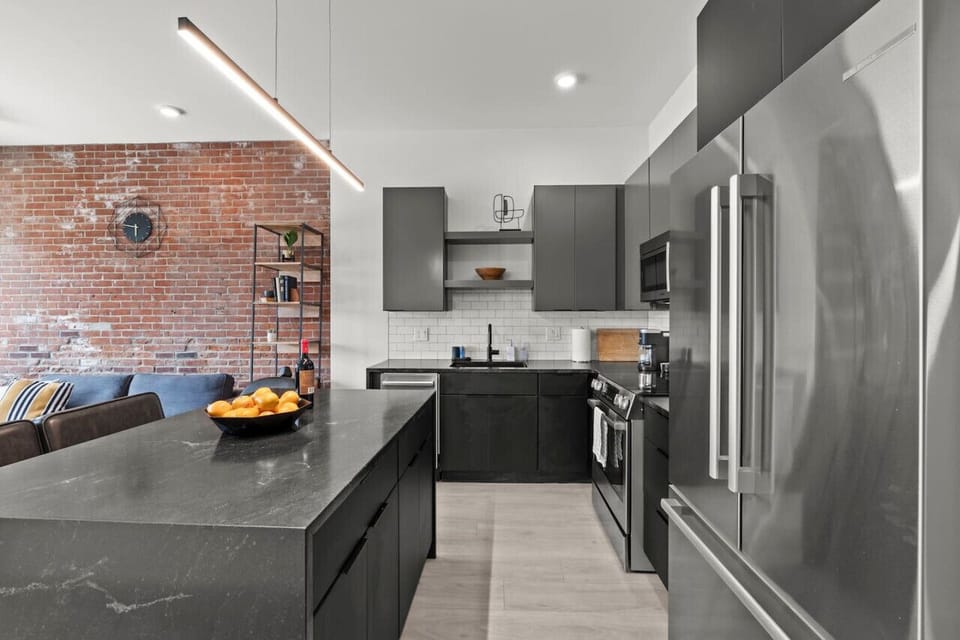 Our cozy kitchen features a charming brick wall and a spacious refrigerator, perfect for storing all your favorite snacks and meals.
