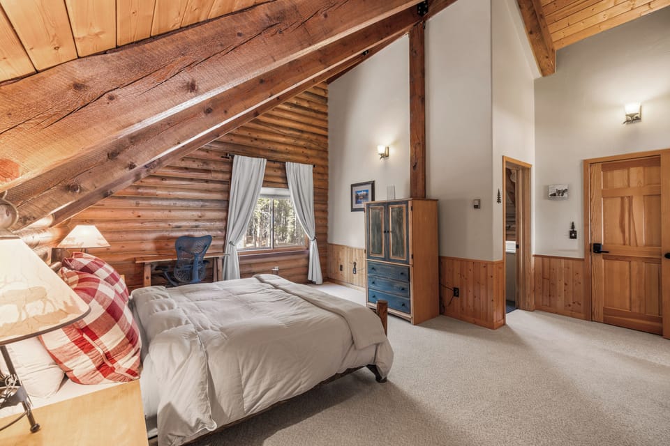 A spacious, enclosed loft bedroom with custom log furnishings, a plush and comfy King size bed, desk space, small Smart TV and En Suite Bathroom.