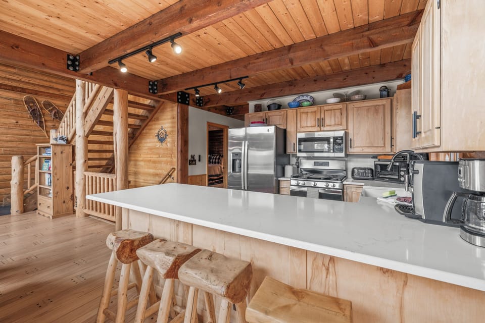 Fully stocked with dishes, kitchen gadgets, and cooking accessories, the kitchen offers a lovely farmhouse sink, top-of-the-line stainless steel appliances and bar style seating for 5 at the kitchen counter.