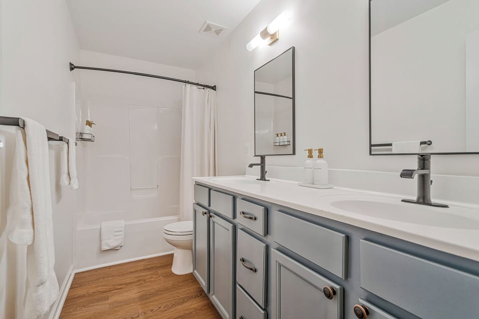 Upstairs bathroom, two‑sink vanity, tub and shower, fully stocked dispensers.
