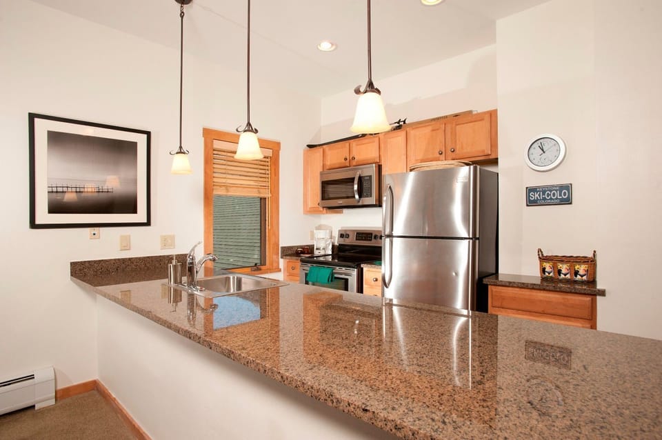 Well-equipped kitchen showcasing modern appliances, granite countertops, and stylish pendant lighting.
