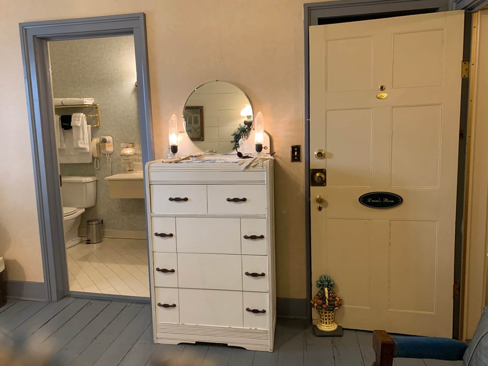 Antique chest of drawers and closet with refrigerator.