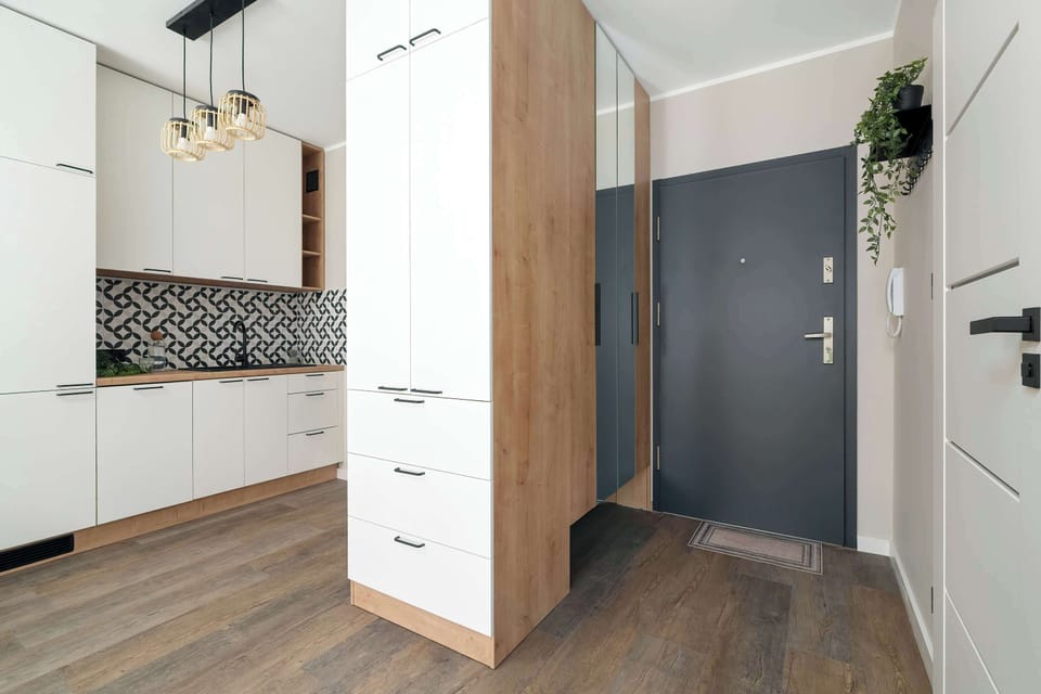 A hallway and kitchen area with built-in cabinets and a patterned backsplash. The space is functional and well-organized with warm wooden accents.