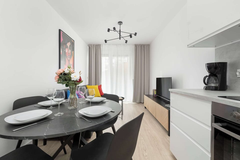 Open-plan kitchen and dining area with white cabinets and a dark round table.