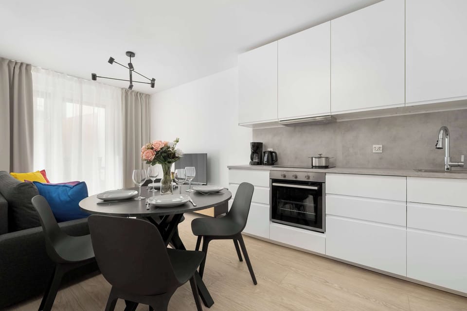 Open-plan kitchen and dining area with white cabinets and a dark round table.