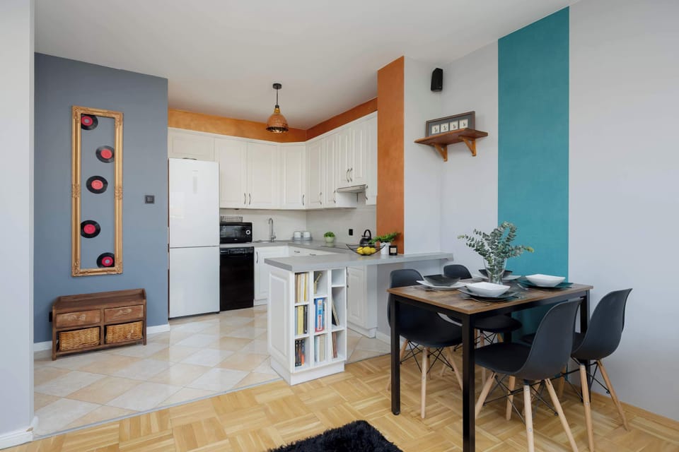 A kitchen and dining nook with sleek cabinetry and stylish wall décor. A small table with chairs completes the cozy dining area.
