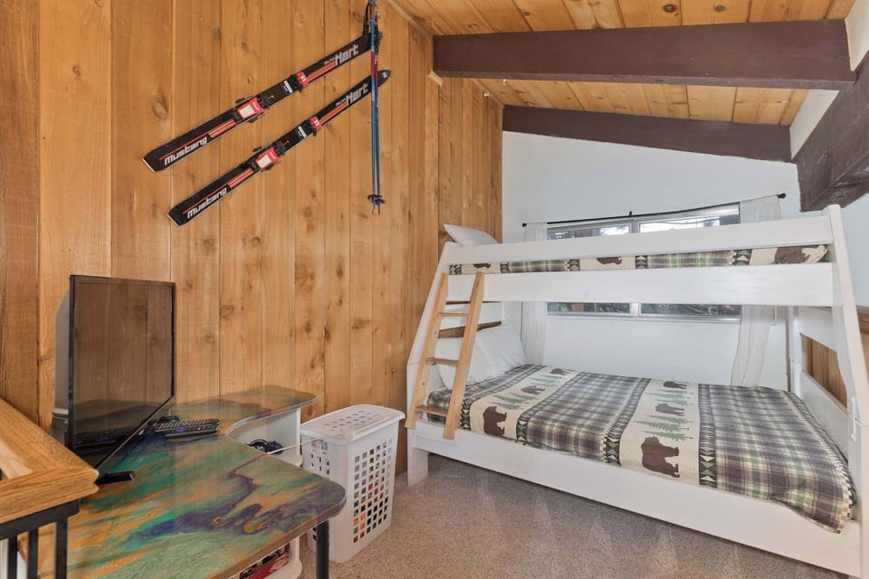Cozy loft w/ bunk bed, mountain decor, and TV/desk area.