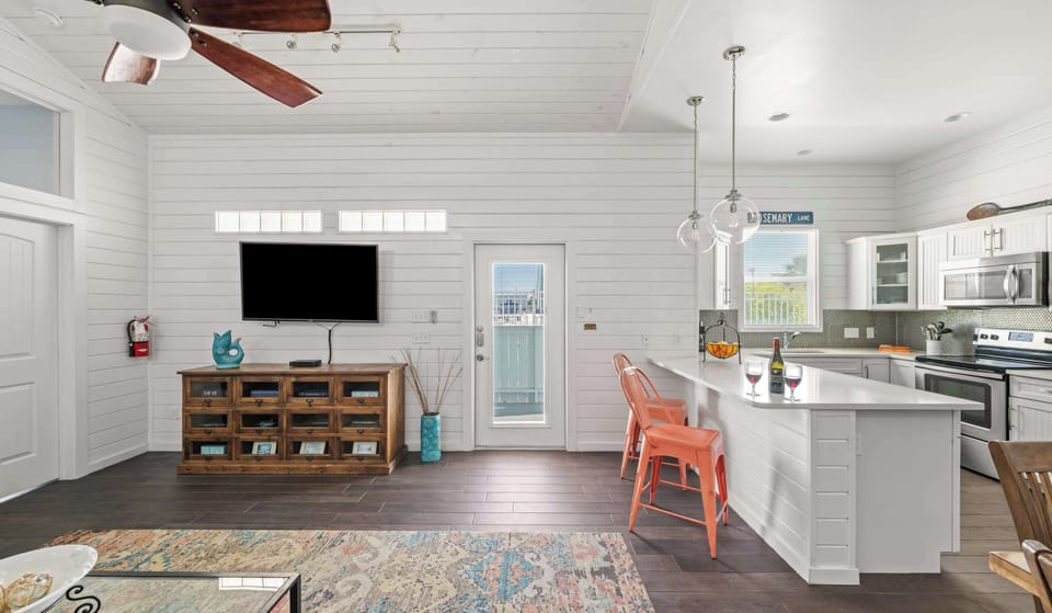 Living & Kitchen — Wall TV, Rustic Apothecary Console, Coral Stools, White Island & 'Rosemary Lane' Sign