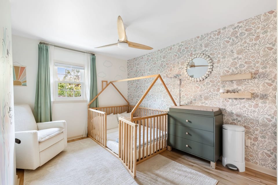 Main level kid's room with nursing chair, diaper pale, changing station, bassinet and monitor. The rails around the full-sized bed are crib height, and the door can be closed for easy containment, no matter your child's age.