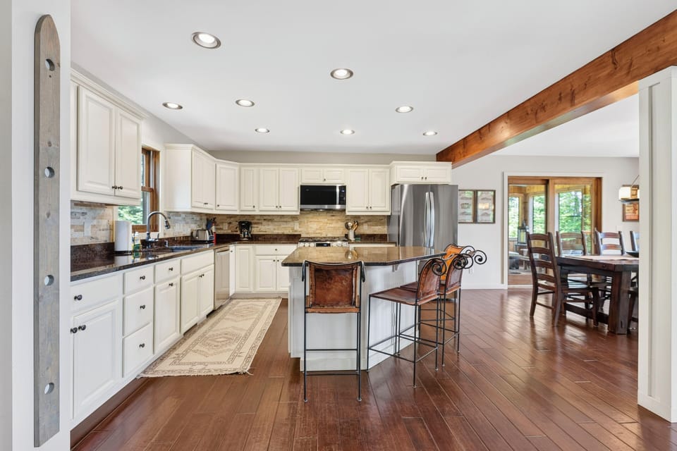 A large white kitchen with dark wood floors and an eat - at island.