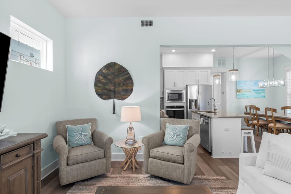 Living room corner showing two upholstered armchairs and a view into the kitchen area.