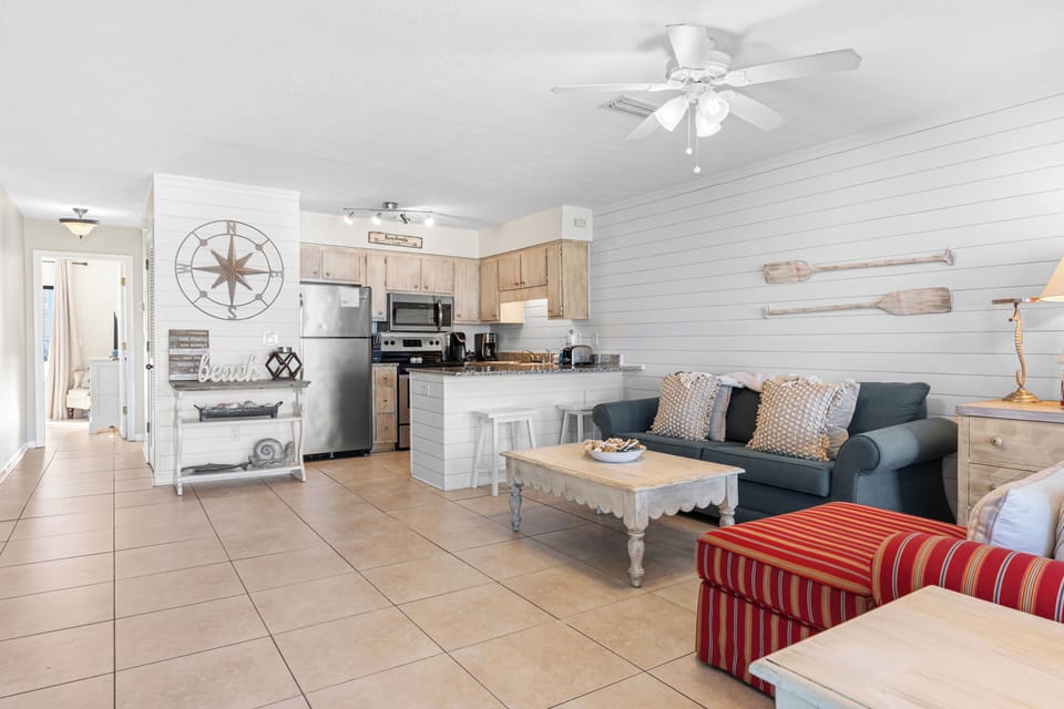 Living and kitchen area with coastal decor and modern appliances.