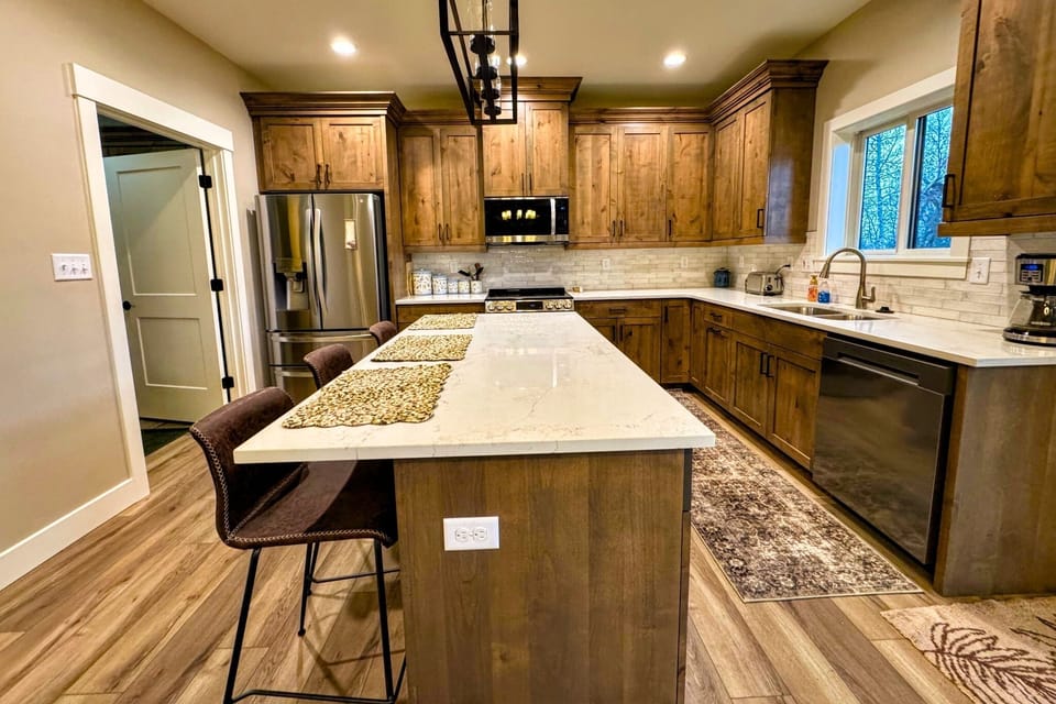 The fully equipped kitchen features custom wood cabinetry, stainless steel appliances, and a large island perfect for gathering.