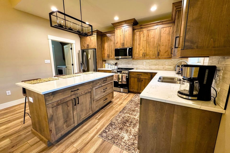 The fully equipped kitchen features custom wood cabinetry, stainless steel appliances, and a large island perfect for gathering.