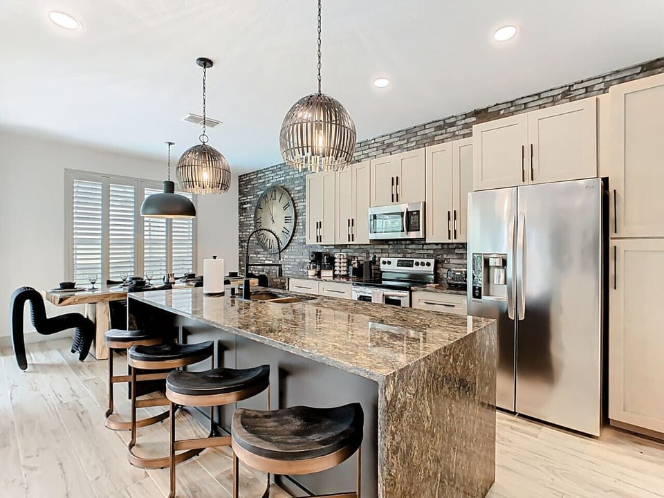 Fully equipped kitchen with stainless steel appliances, spacious granite island, and seating ideal for meals or casual conversations.