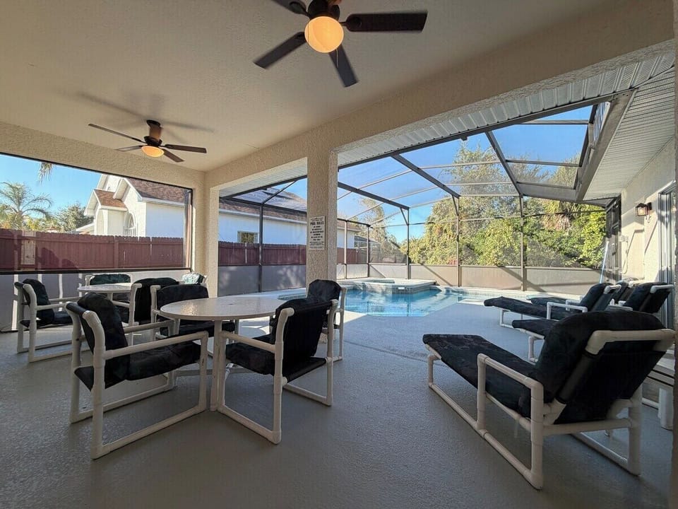 This spacious covered patio features a dining table, ceiling fans, and direct access to the pool area. It’s the perfect spot for outdoor meals, morning coffee, or relaxing with family while enjoying the warm Florida breeze.