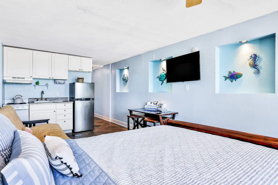 Inviting beach stay studio featuring a cozy bed, sleeper sofa, kitchenette, and coastal décor. Relax after a day at the beach in this open, airy space designed for comfort, convenience, and seaside living.